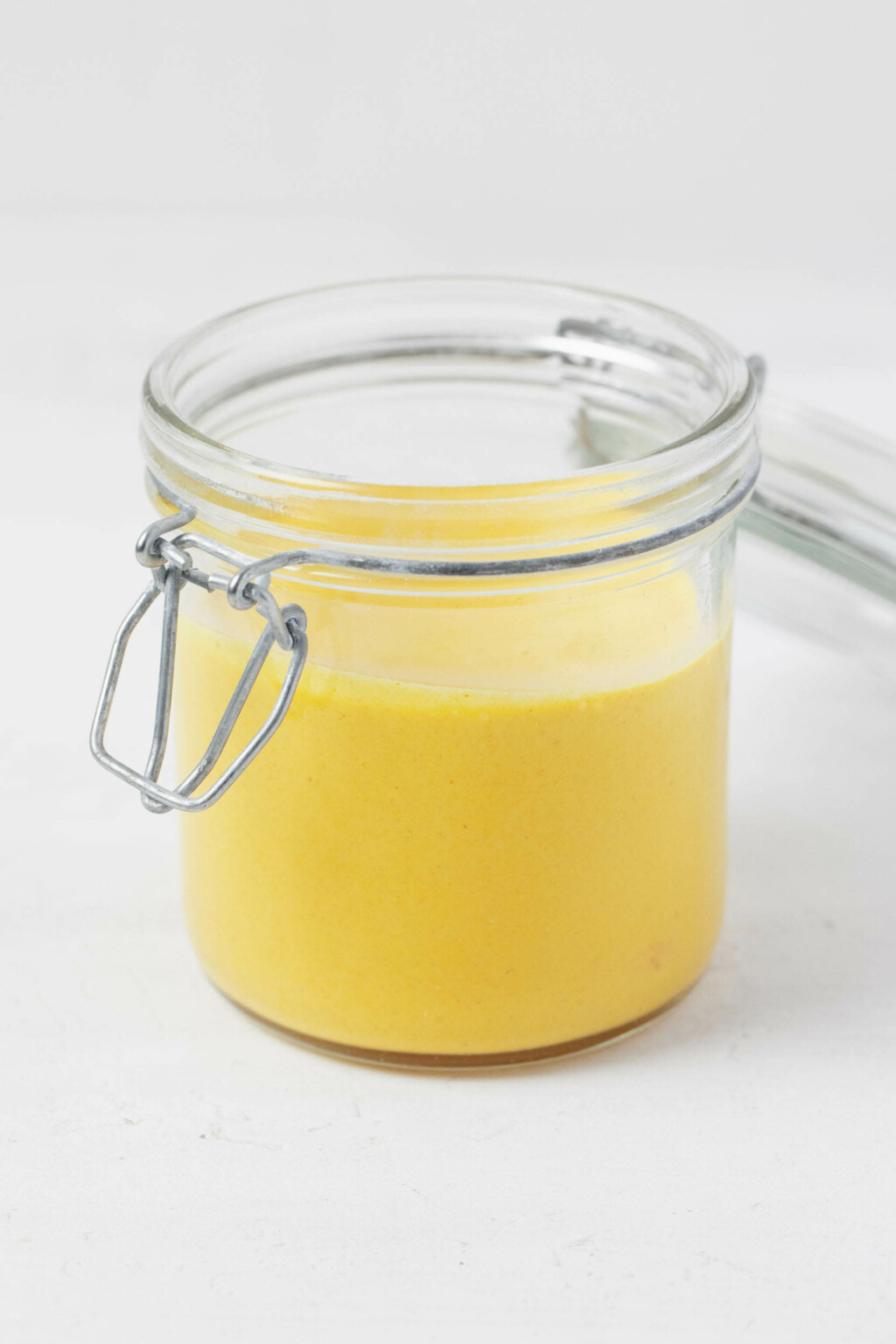 A sideways image of a mason jar, which has been filled with an electric gold, creamy sauce.