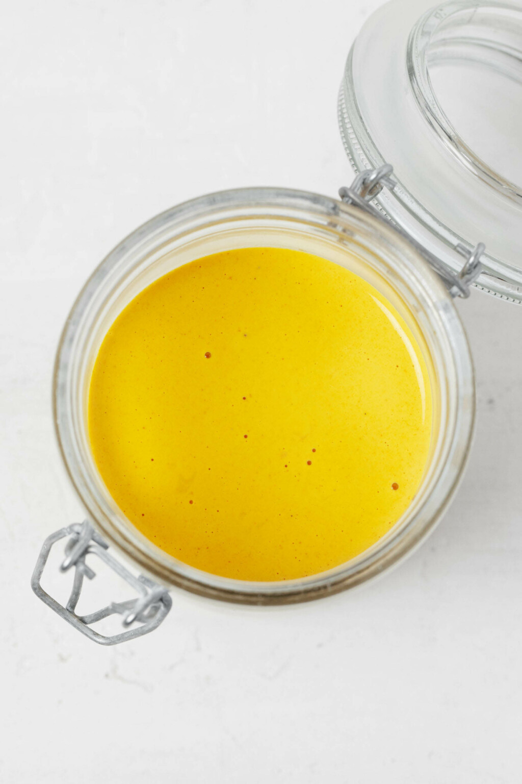 An overhead image of a mason jar that is filled with a creamy yellow sauce.